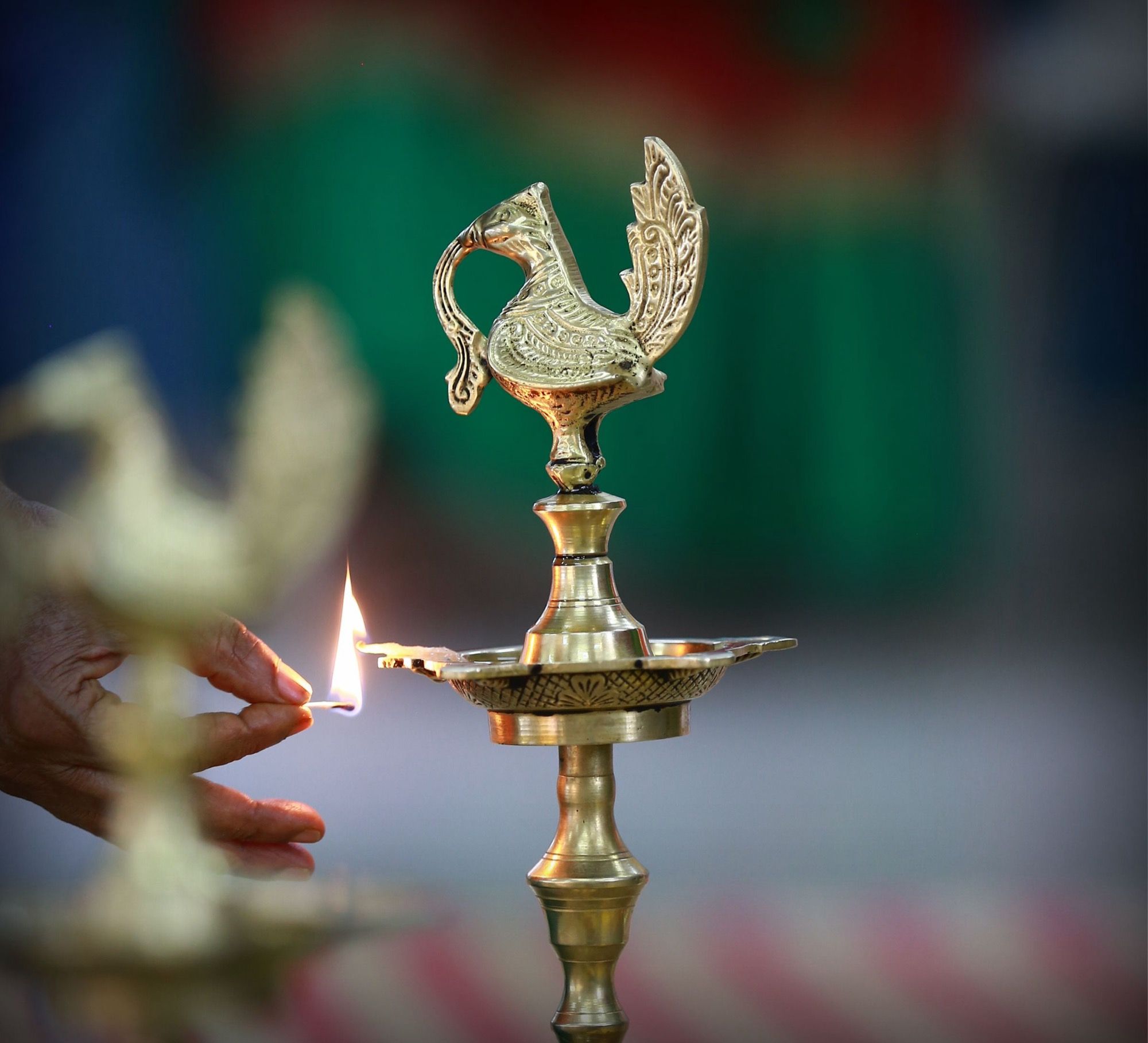 A hand lighting a brass lamp at an opening